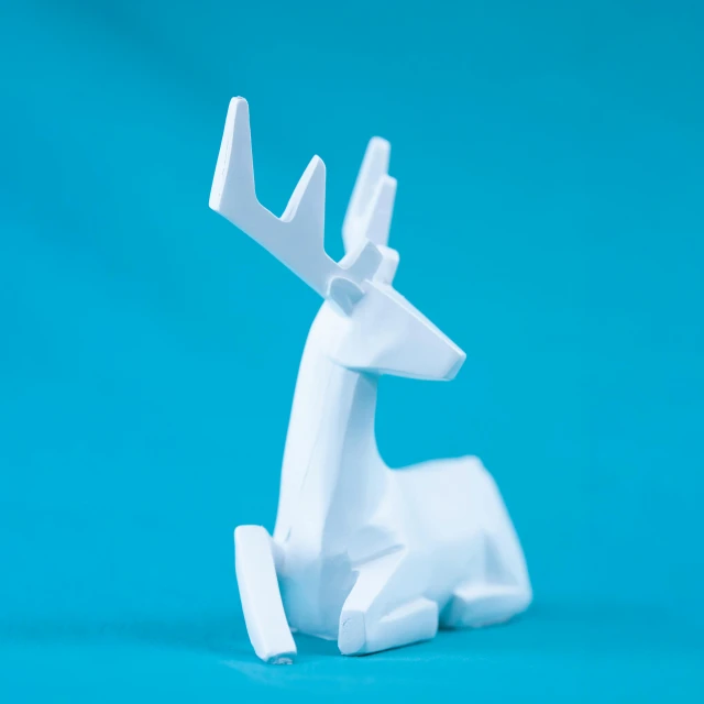 a close up of a toy deer on a blue background, a low poly render, pexels contest winner, made of all white ceramic tiles, ornament, resting, medium close shot