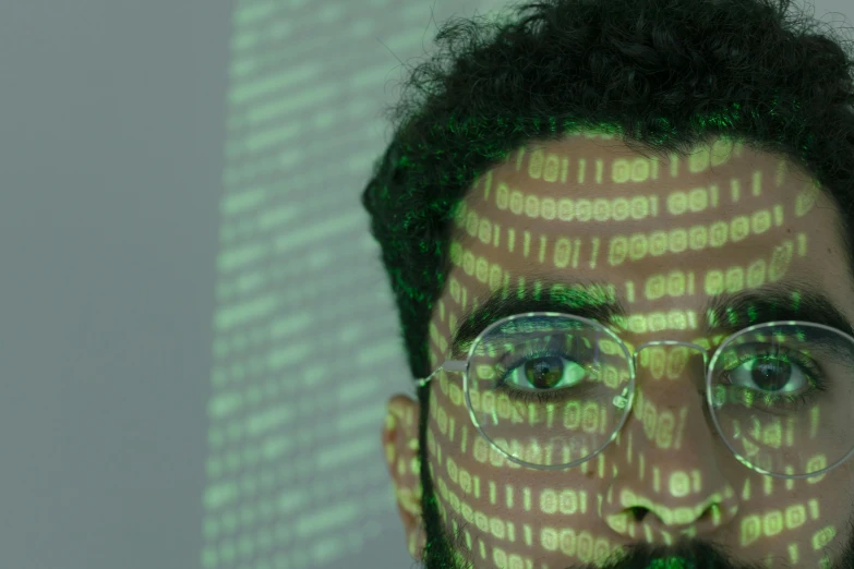a man with glasses and a beard in front of a computer screen, a hologram, by Carey Morris, pexels, ascii art, green skin with scales, aida muluneh, professional closeup photo, a person standing in front of a
