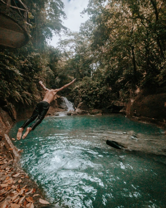 a man jumping off a cliff into a river, by Byron Galvez, pexels contest winner, sumatraism, poolside, in a tropical forest, 👰 🏇 ❌ 🍃, zach hill