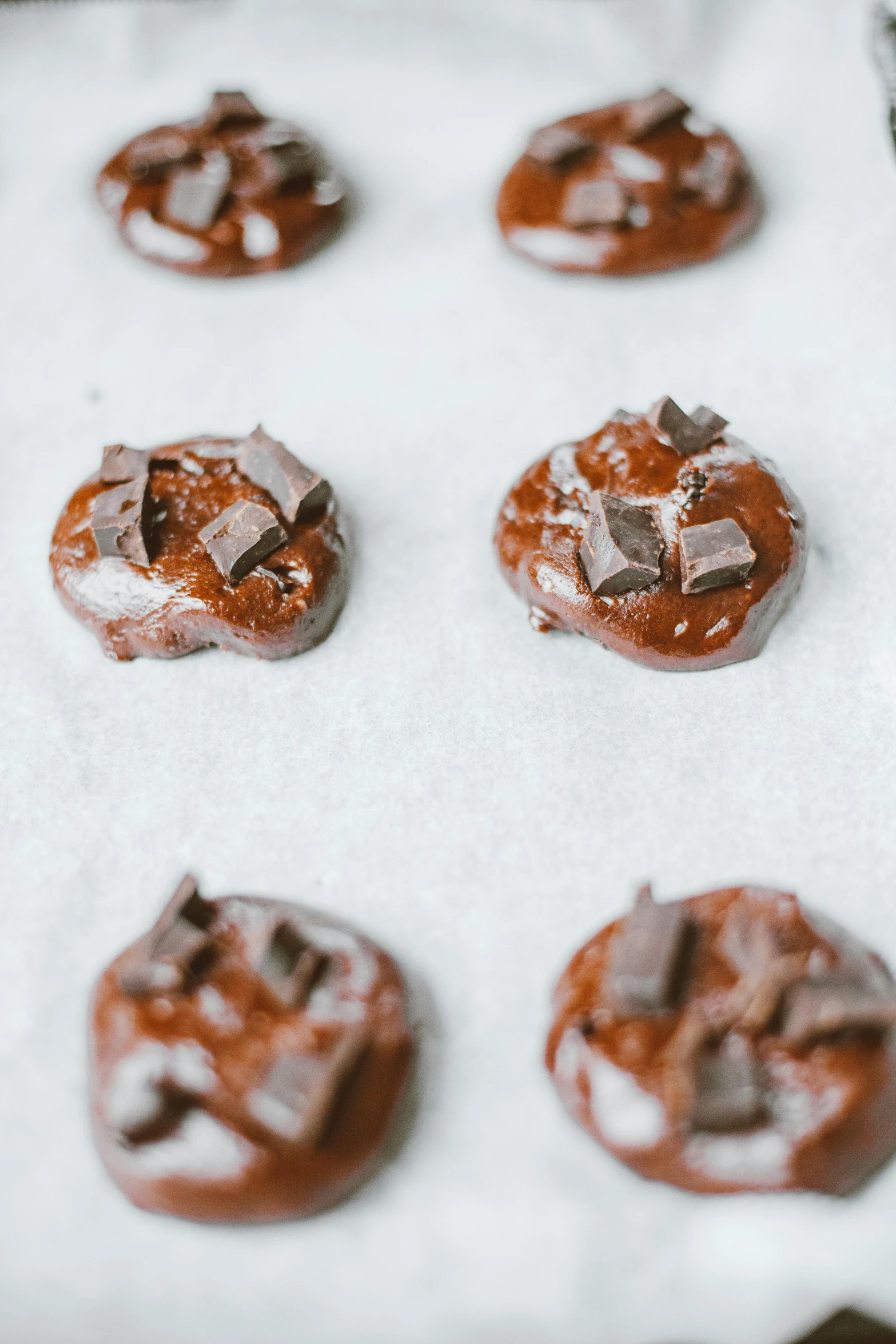 a tray filled with chocolate covered cookies on top of a table, by Jessie Algie, unsplash, process art, melted wax, on grey background, bottom body close up, thumbnail