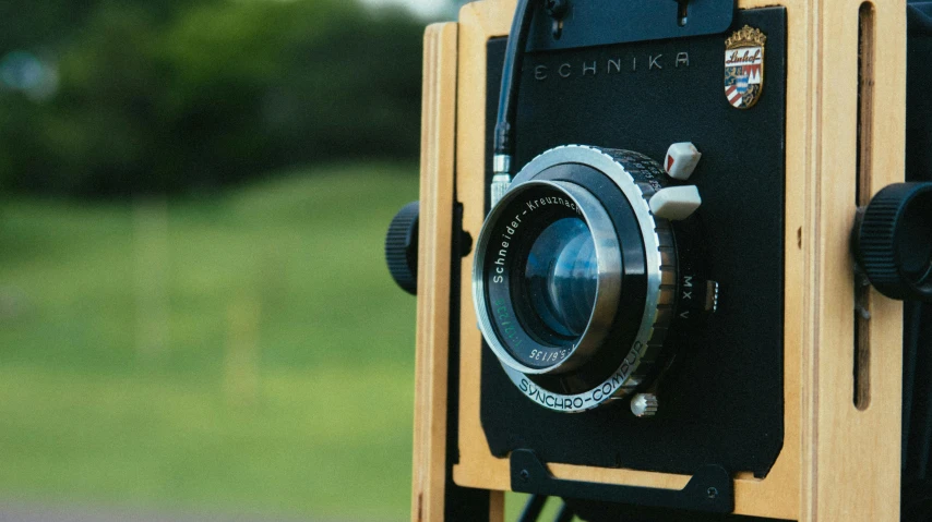 a close up of a camera with a field in the background, by Yasushi Sugiyama, unsplash, photorealism, a wooden, auto graflex, medium format, portrait n - 9