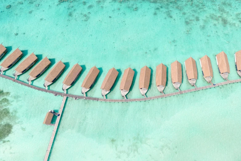 a group of boats sitting on top of a body of water, a digital rendering, pexels contest winner, hurufiyya, huts, drone photo, clear and sunny, 🦩🪐🐞👩🏻🦳