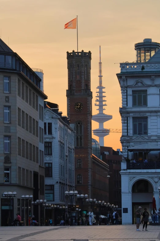 a group of people walking down a street next to tall buildings, pexels contest winner, berlin secession, minarets, evening light, brutalist buildings tower over, ravnica