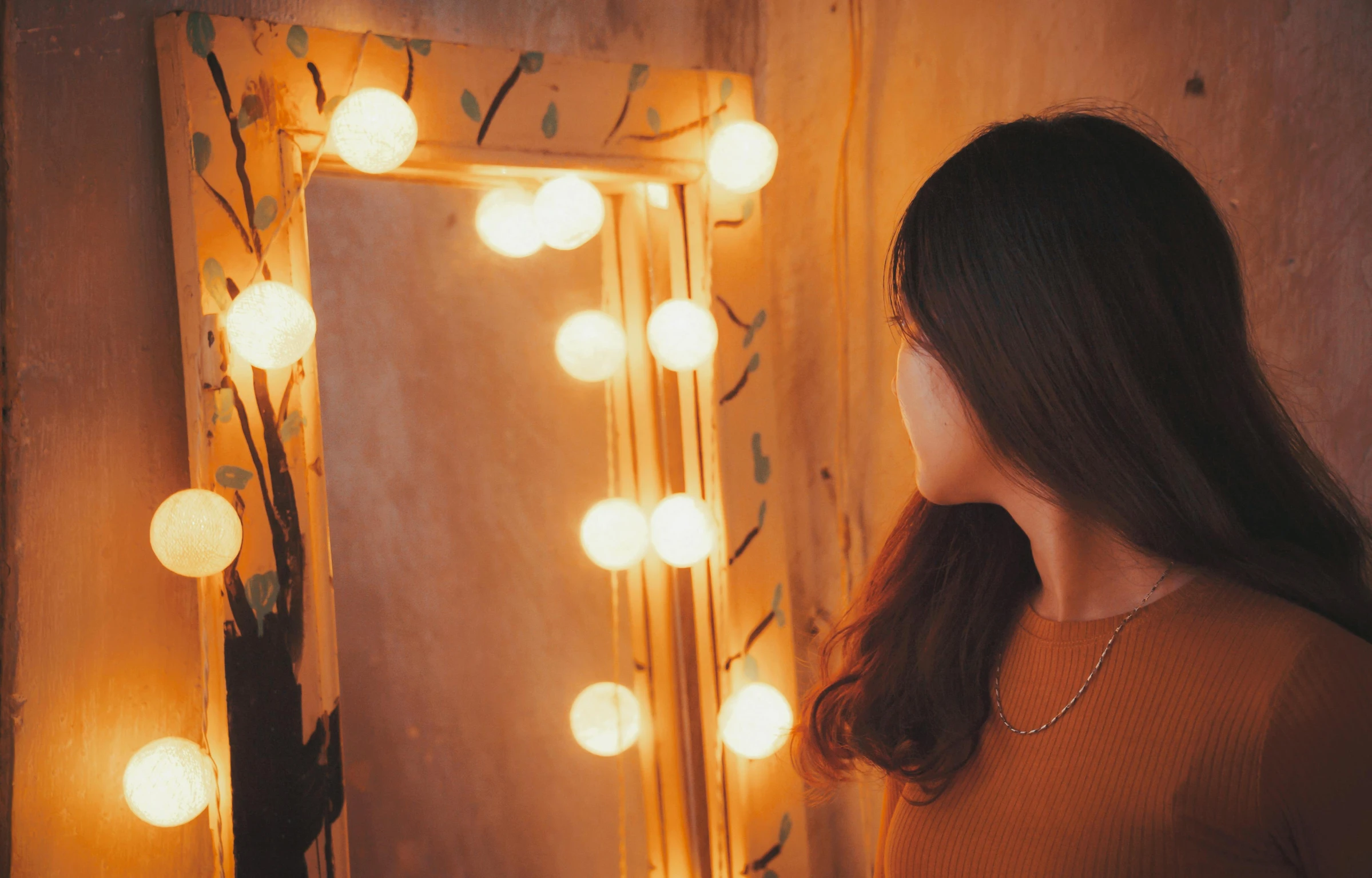 a woman looking at her reflection in a mirror, inspired by Elsa Bleda, pexels contest winner, beautiful kawaii lighting, theater dressing room, orange glow, lamp ( ( ( mirror ) ) ) )