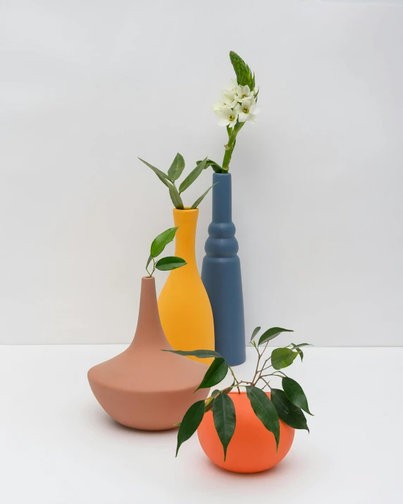 three vases sitting next to each other on a table, a still life, inspired by Giorgio Morandi, unsplash, new sculpture, colorful bottles and plants, dark grey and orange colours, side profile shot, petite pear slim figure