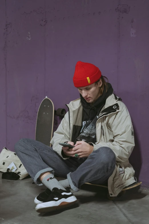 a man sitting on the ground with a skateboard, inspired by Seb McKinnon, trending on pexels, graffiti, he has a red hat, cell phone, movie still of a tired, profile picture