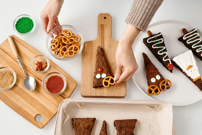 a person cutting a piece of cake on a cutting board, a picture, by Julia Pishtar, trending on pexels, gingerbread people, cone shaped, chocolate candy bar packaging, plated arm