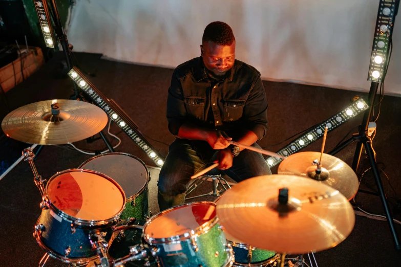 a man sitting in front of a drum set, by David Brewster, pexels contest winner, hurufiyya, gregory euclide, worship, rectangle, coloured