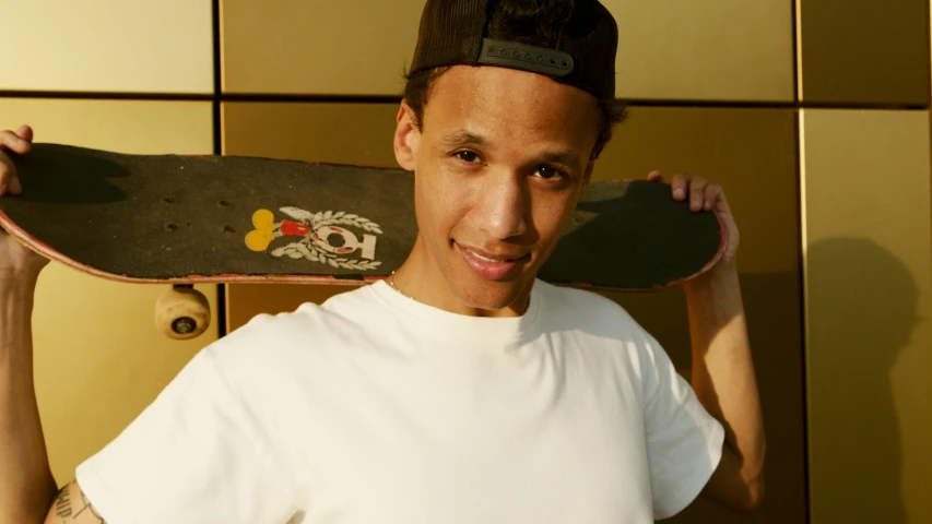 a man holding a skateboard over his head, portrait of danny gonzalez, official store photo, smiling for the camera, large forehead