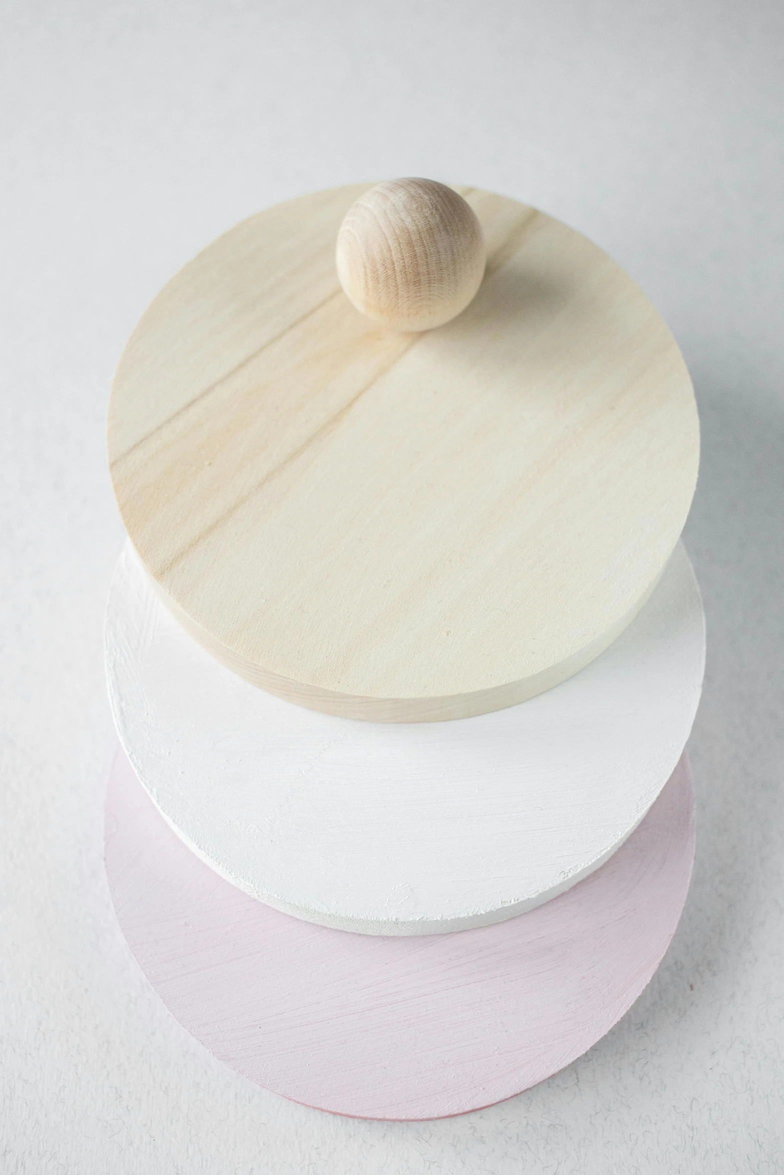 three wooden plates stacked on top of each other, inspired by Anish Kapoor, process art, white and pink, metal lid, nordic pastel colors, detail shot