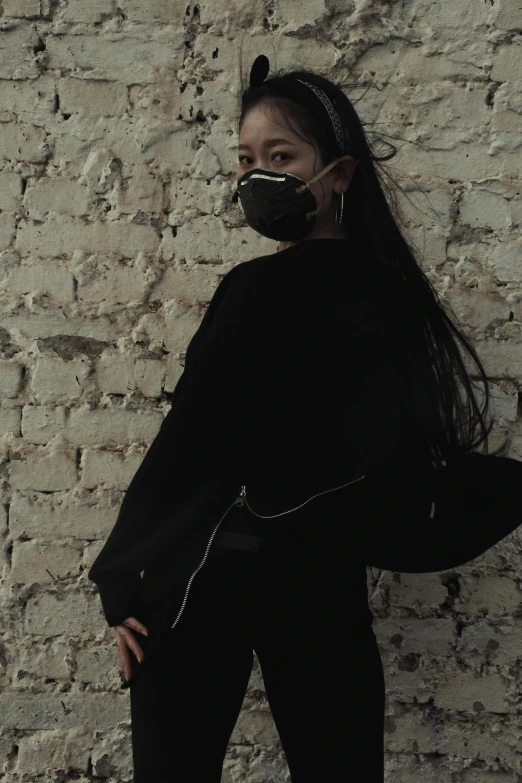 a woman standing in front of a brick wall, an album cover, inspired by Zhu Da, trending on pexels, wearing all black mempo mask, ulzzang, cropped shirt with jacket, y 2 k cybercore