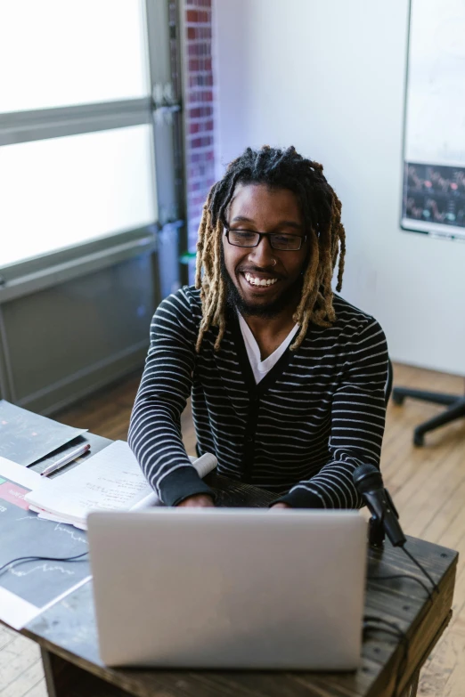 a man sitting in front of a laptop computer, pexels contest winner, black arts movement, slight nerdy smile, standing on a desk, dreadlock black hair, mit technology review