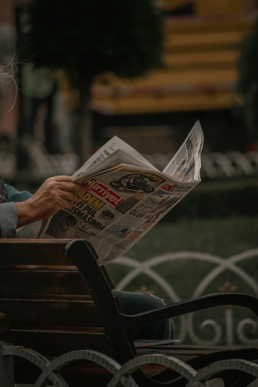 a woman sitting on a bench reading a newspaper, pexels contest winner, paul barson, words, splash image, mid shot photo