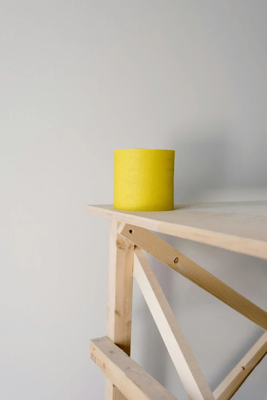 a yellow candle sitting on top of a wooden table, inspired by Sarah Lucas, minimalism, shelf, vibrant threads, experimental studio light, product view