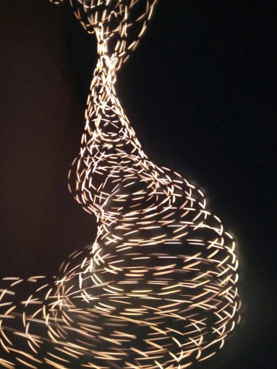 a close up of a light painting on a black background, reddit, graceful curves, photo taken with an iphone, made of wire, spire