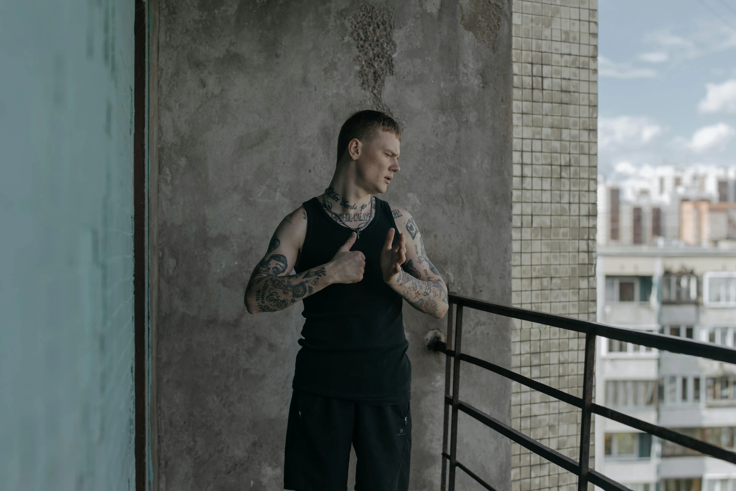 a man with tattoos standing on a balcony, a tattoo, by Attila Meszlenyi, pexels contest winner, ernest khalimov body, a pale skin, she is wearing a black tank top, 8k octan photo