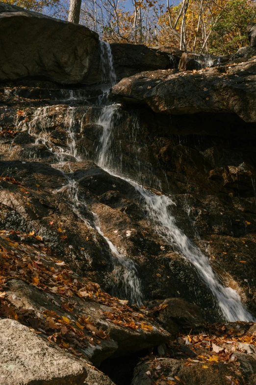 a man standing on top of a rock next to a waterfall, inspired by Elsa Bleda, unsplash contest winner, closeup 4k, autumnal, small stream, today\'s featured photograph 4k