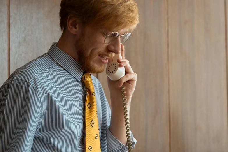 a man in a blue shirt and yellow tie talking on a phone, trending on pexels, ron weasley, ed sheeran, vintage aesthetic, highly detailed