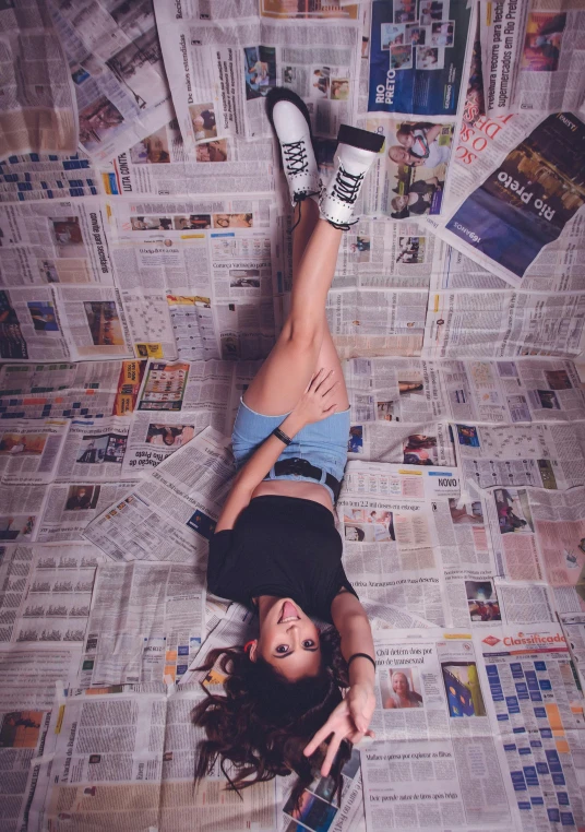 a woman laying on top of a pile of newspapers, unsplash contest winner, madison beer girl portrait, full body! shot, high angle shot, with pop punk style