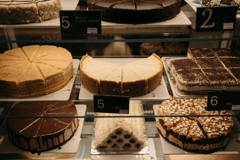 a display case filled with lots of different types of cakes, a photo, trending on pexels, manuka, 2 0 0 0's photo, fan favorite, pi - slices
