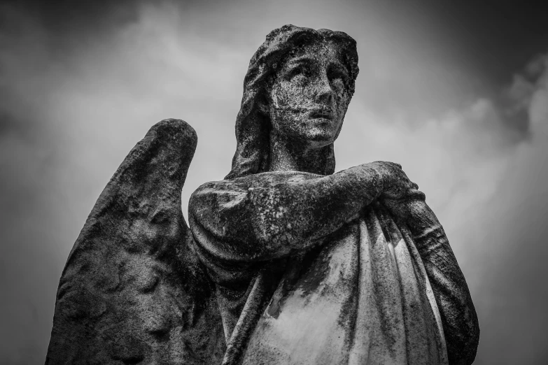 a black and white photo of a statue of an angel, a statue, by Daniel Lieske, pexels contest winner, gothic art, black rock statue material, looking the camera, winged, southern gothic art