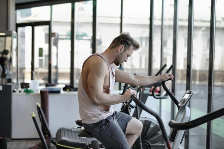 a man riding a stationary bike in a gym, by Adam Marczyński, pexels contest winner, figuration libre, avatar image, low quality photo, looking across the shoulder, profile image