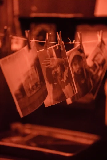 a bunch of photos hanging on a clothes line, happening, warm orange lighting, profile image, ( ( theatrical ) ), smoldering