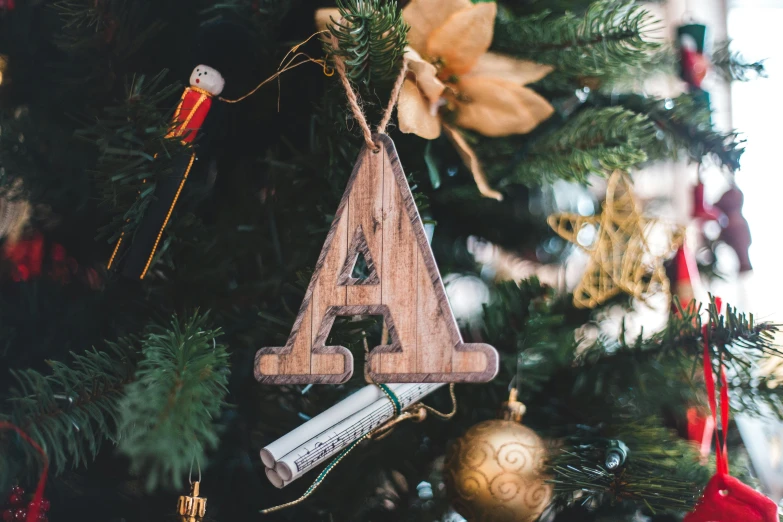 a wooden letter ornament hanging from a christmas tree, by Emma Andijewska, pexels contest winner, teepee, arnold armitage, an architectural, a handsome