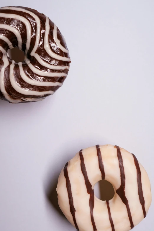 two donuts sitting next to each other on a table, a picture, by Doug Ohlson, unsplash, on a pale background, fuji choco, glazed, thick lines