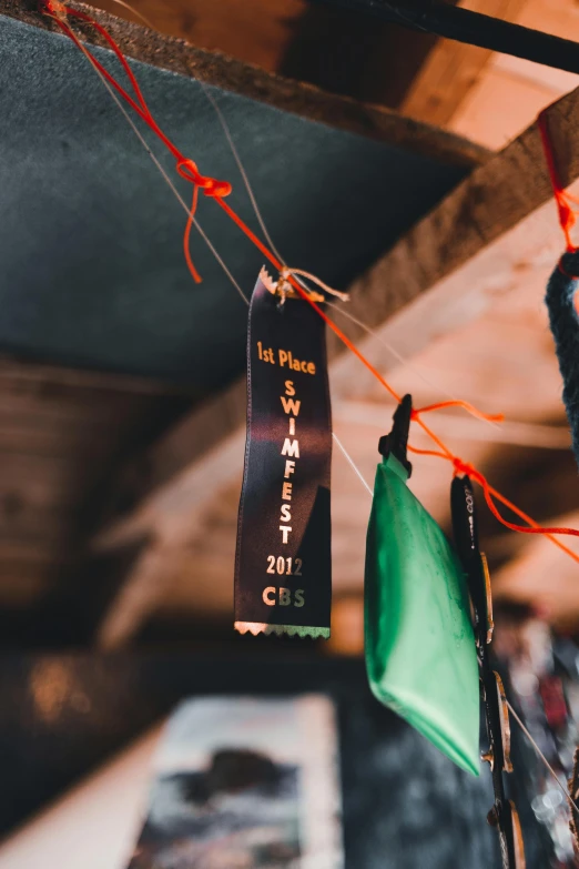 a couple of tags hanging from a string, by Whitney Sherman, unsplash contest winner, wide ribbons, indoor picture, low detail, community celebration