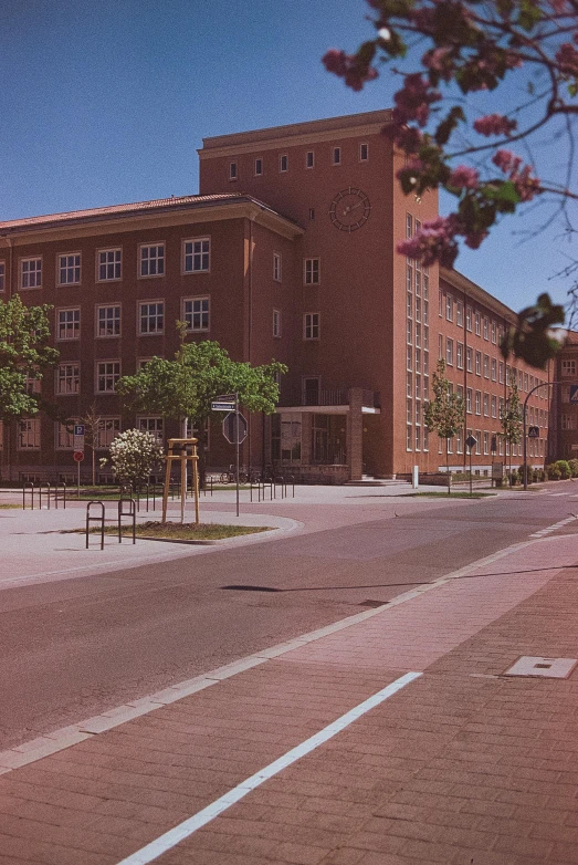 a large brick building sitting on the side of a road, a colorized photo, by Carlo Carrà, heidelberg school, 1980s photograph, medical complex, madrid, japanese high school