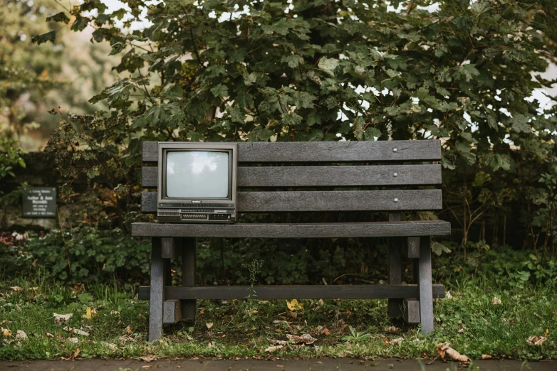 an old television sitting on top of a wooden bench, inspired by Banksy, unsplash, 1 9 8 0 s computers, a park, ignant, elliot alderson