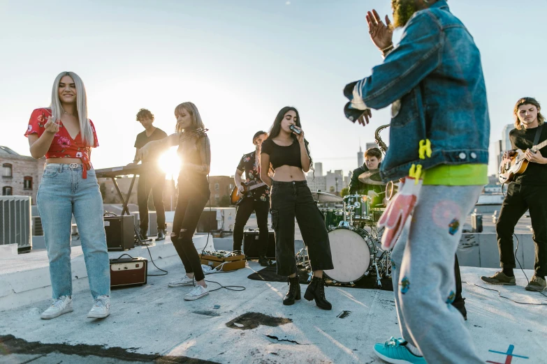 a group of people standing on top of a roof, an album cover, unsplash, happening, charli bowater, performing a music video, brightly-lit, in a rooftop