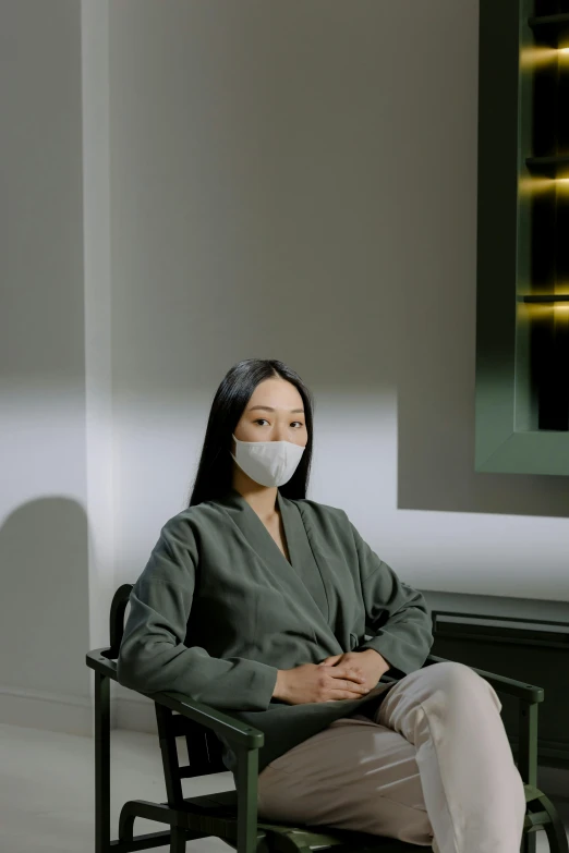 a woman sitting in a chair wearing a face mask, inspired by Fei Danxu, interview, grey, irelia, surgeon