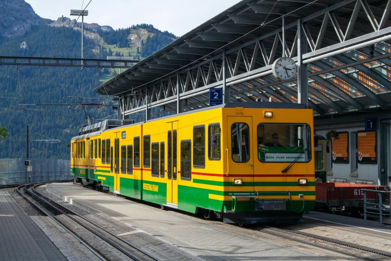 a yellow and green train pulling into a train station, by Karl Stauffer-Bern, pexels contest winner, square, trams, panoramic, fan favorite