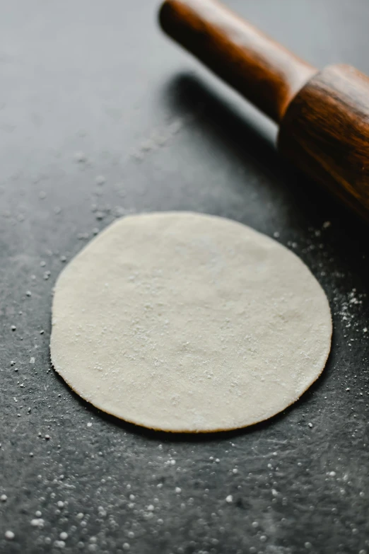 a close up of a dough on a table with a rolling pin, unsplash, flat pancake head, silver，ivory, slate, petite