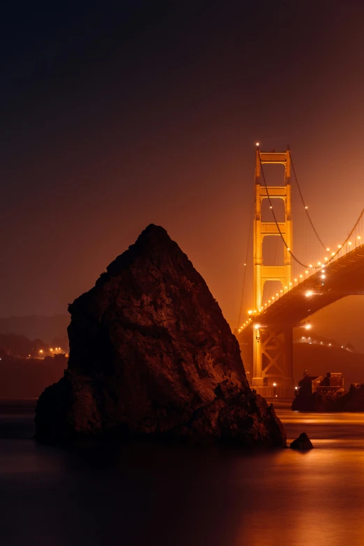 the golden gate bridge is lit up at night, pexels contest winner, renaissance, medium format. soft light, rock formations, full frame image