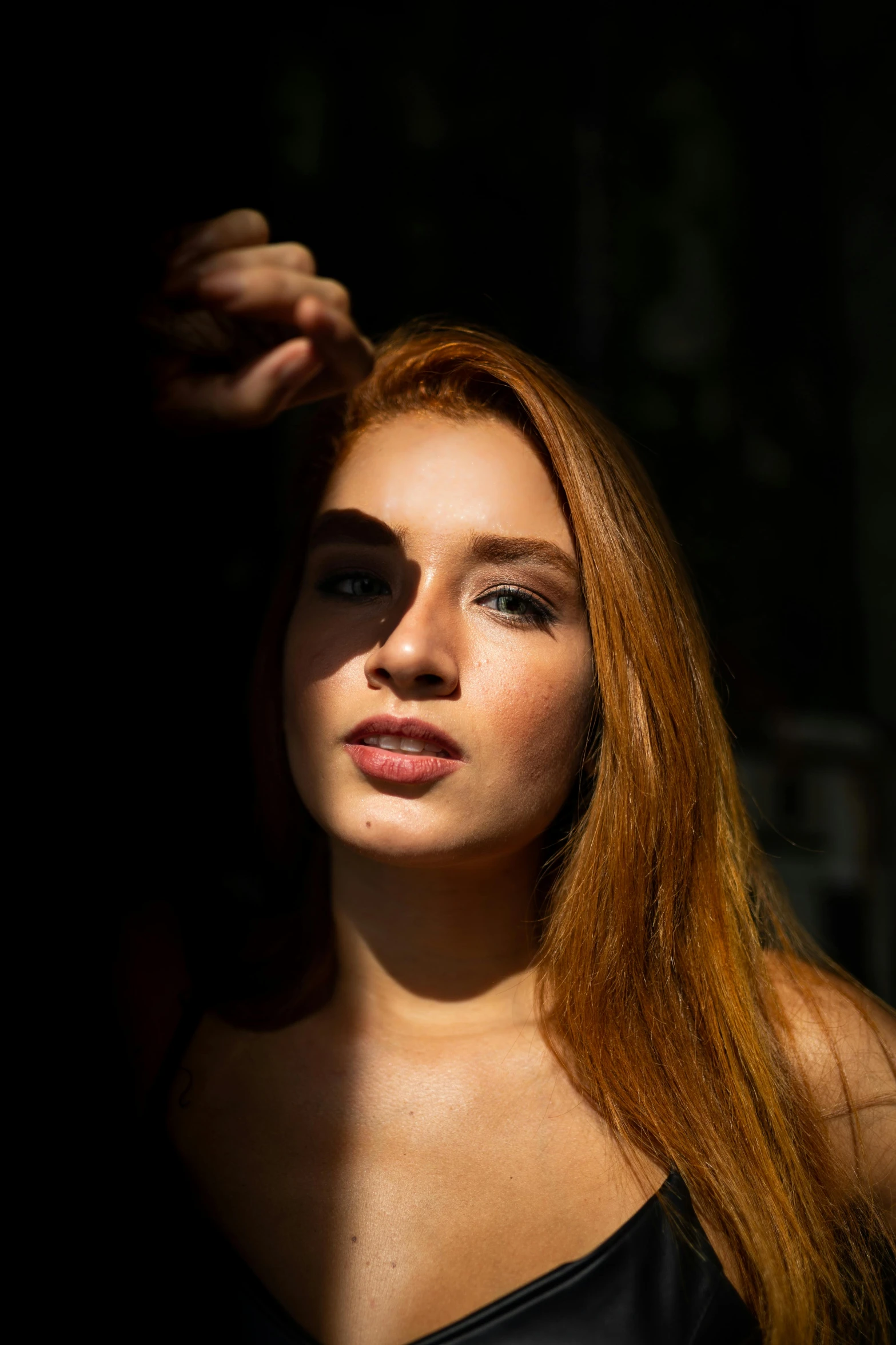 a woman in a black dress posing for a picture, a portrait, by Sven Erixson, pexels contest winner, long glowing red hair, light and shadow effects, young woman's face, sun behind him