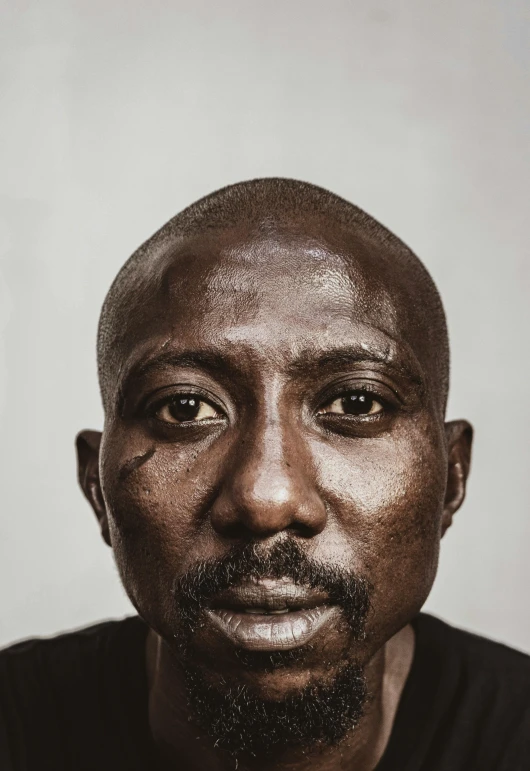 a close up of a person wearing a black shirt, an album cover, by David Begbie, pexels contest winner, hyperrealism, african facial features, alec soth : : love, portrait of a rugged warrior, tupac