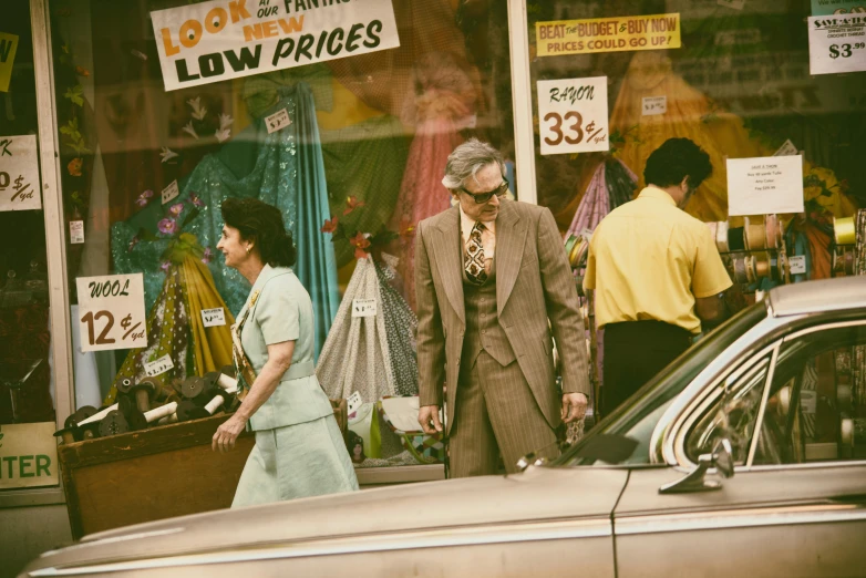a man and woman walking in front of a store, a colorized photo, by Lee Loughridge, pexels contest winner, 1 9 7 0 s car window closeup, in a gold suit, selling his wares, american gods