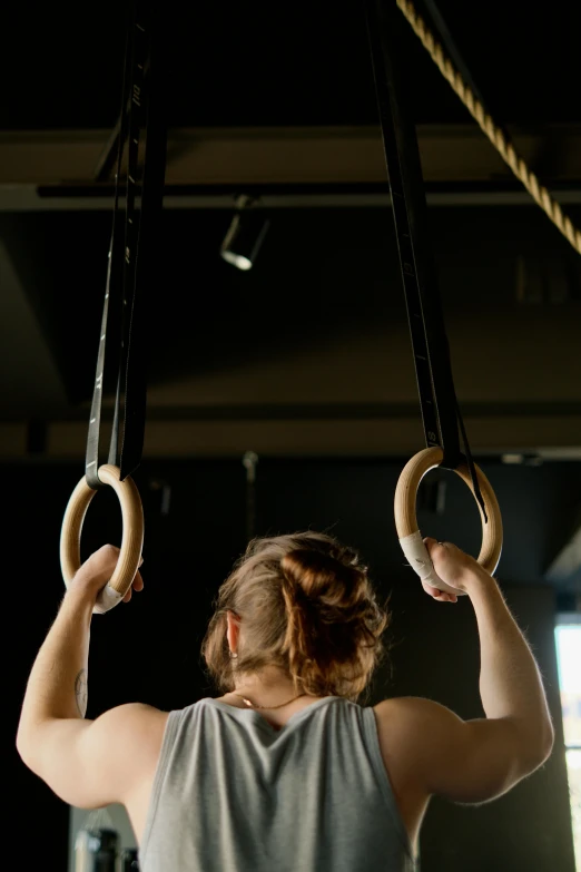 a woman hanging on rings in a gym, trending on pexels, renaissance, shot from the back, oscar winning, large)}], square