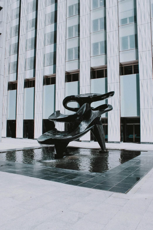 a black and white photo of a sculpture in front of a building, an abstract sculpture, by Alexander Stirling Calder, unsplash, made of liquid metal and marble, corporate memphis, sculpture made of water, sitting