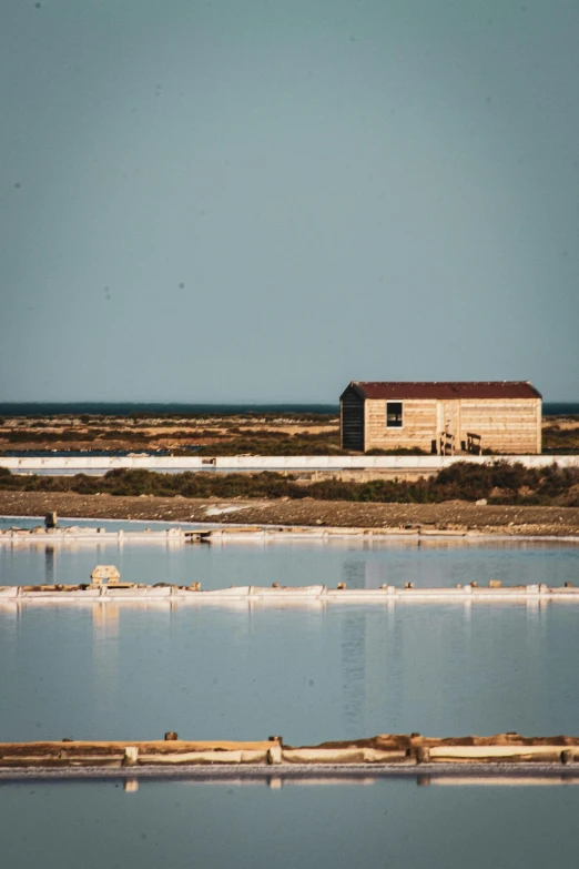 a large body of water with a building in the background, by Julia Pishtar, les nabis, salt dunes, farms, high quality image, mining