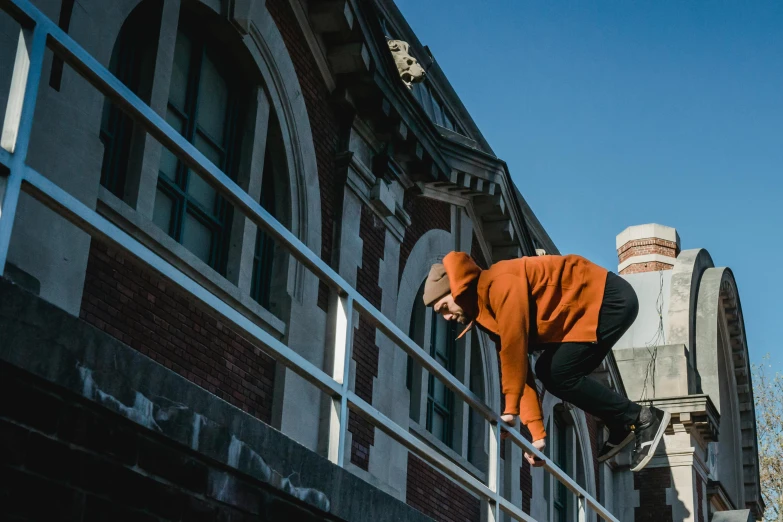 a man flying through the air while riding a skateboard, by Lee Loughridge, unsplash, long orange sweatshirt, sits on a rooftop, parkour, cinematic outfit photo