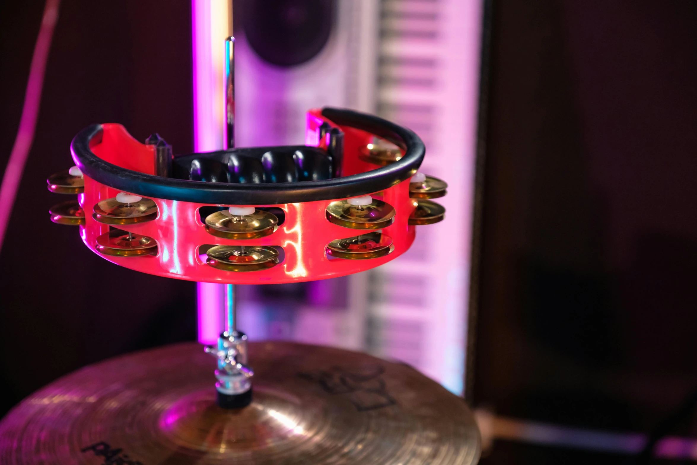 a musical instrument sitting on top of a drum, by Julia Pishtar, kinetic art, red and obsidian neon, middle close up shot, studio lights, bangles