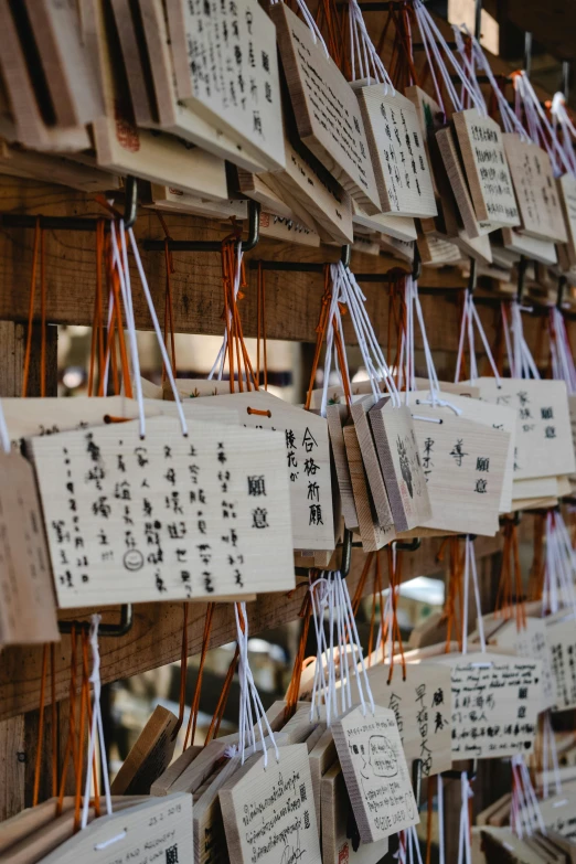 a bunch of wooden signs hanging on a wall, inspired by Sesshū Tōyō, unsplash, pagoda with a lot of wind chimes, cards, 2019 trending photo, signatures