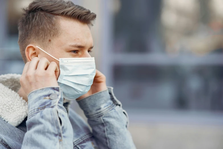 a man wearing a face mask while talking on a cell phone, an album cover, by Adam Marczyński, shutterstock, 15081959 21121991 01012000 4k, disease, male teenager, worried