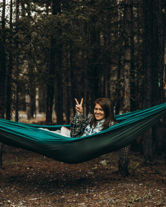 a woman laying in a hammock in the woods, pexels contest winner, peace sign, teal, lightroom preset, lgbtq