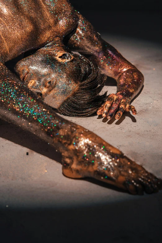 a woman covered in glitter laying on the ground, art photography, man is with black skin, resin and clay art, 2019 trending photo, synthetic bio skin