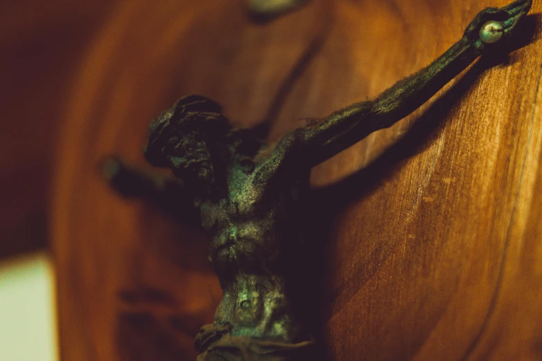 a close up of a statue of a person on a cross, a bronze sculpture, by Elsa Bleda, pexels contest winner, renaissance, on a wooden plate, 33mm photo, bronze, seductive and powerful